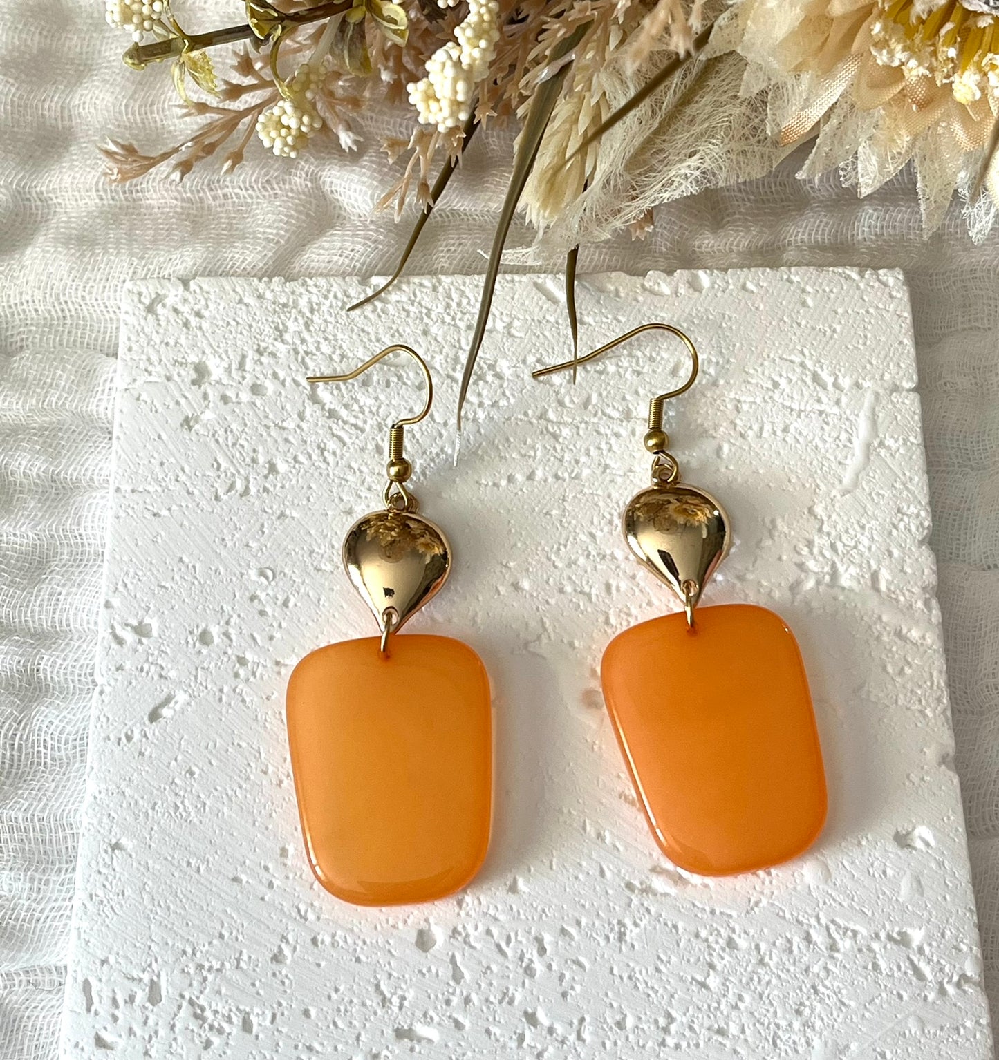 Boucles d'oreilles fantaisie fait main.
Crochets en acier inox doré.
Connecteurs goutte dorés.
Pendentifs trapèze en résine orange.
Bijou fantaisie fait main.