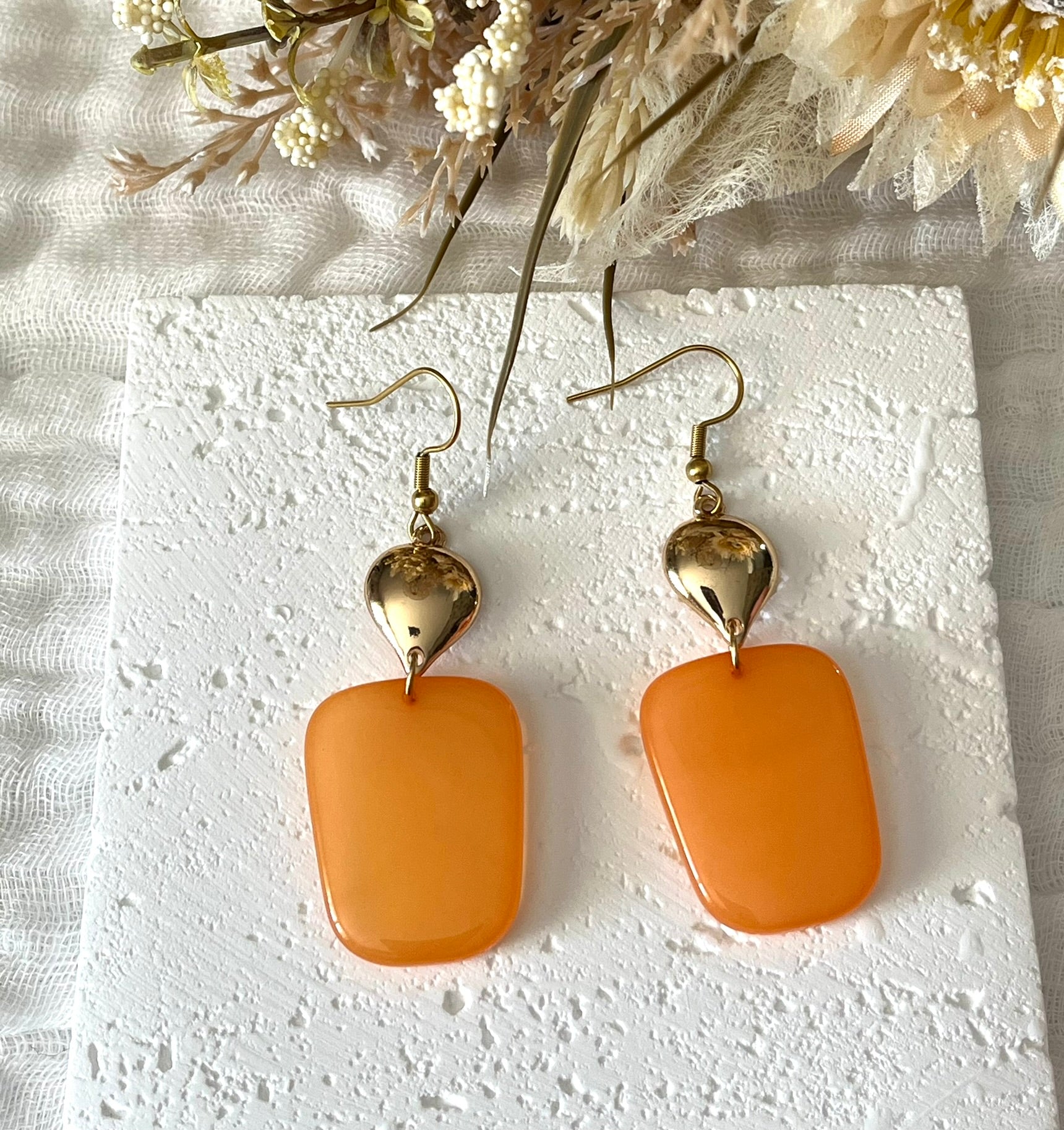Boucles d'oreilles fantaisie fait main.
Crochets en acier inox doré.
Connecteurs goutte dorés.
Pendentifs trapèze en résine orange.
Bijou fantaisie fait main.