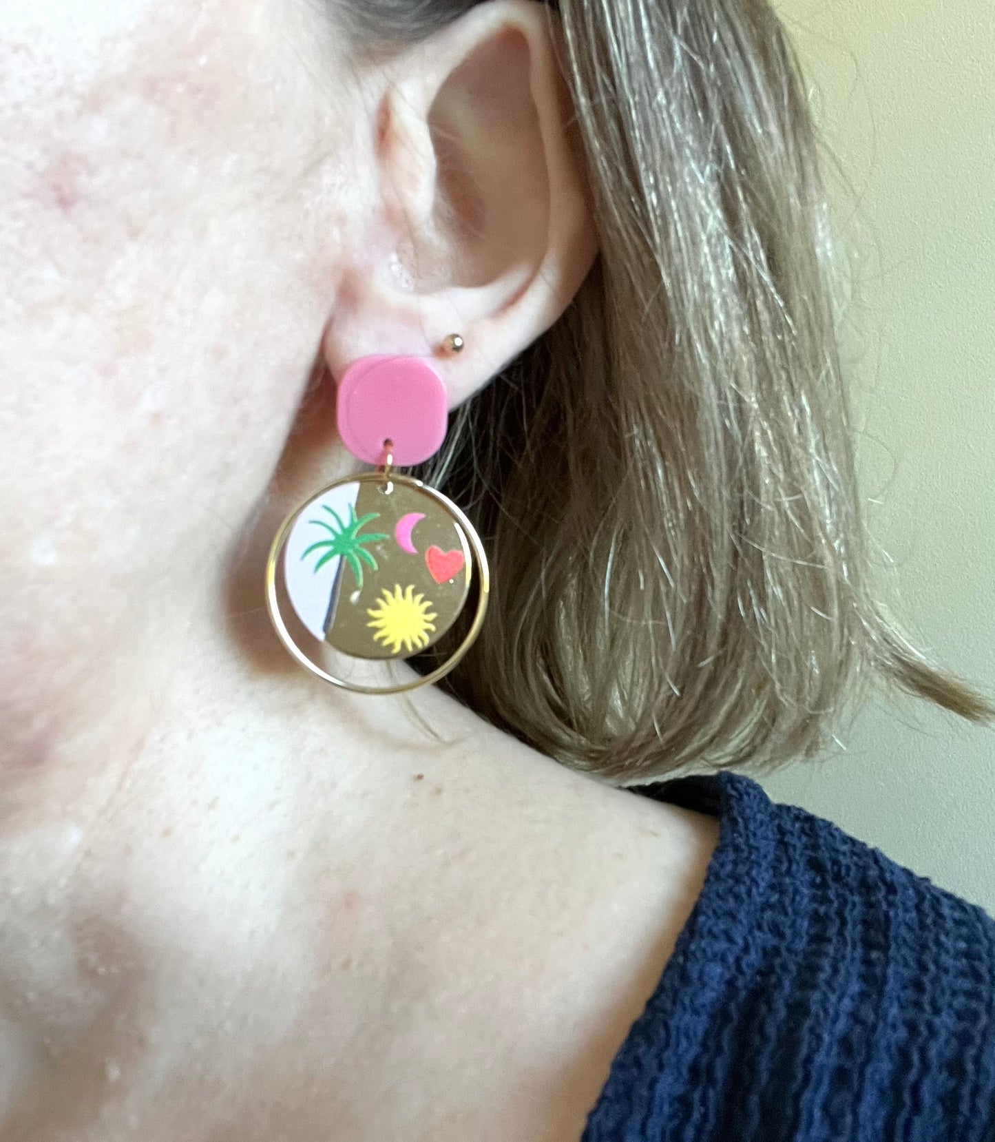 Boucles d'oreilles fantaisie fait main.
Clous d'oreilles en acrylique rose, anneaux fermés en laiton or 18k, pendentifs ronds bicolores doré et rose imprimé palmier, coeur, lune, soleil.
Bijou fantaisie fait main