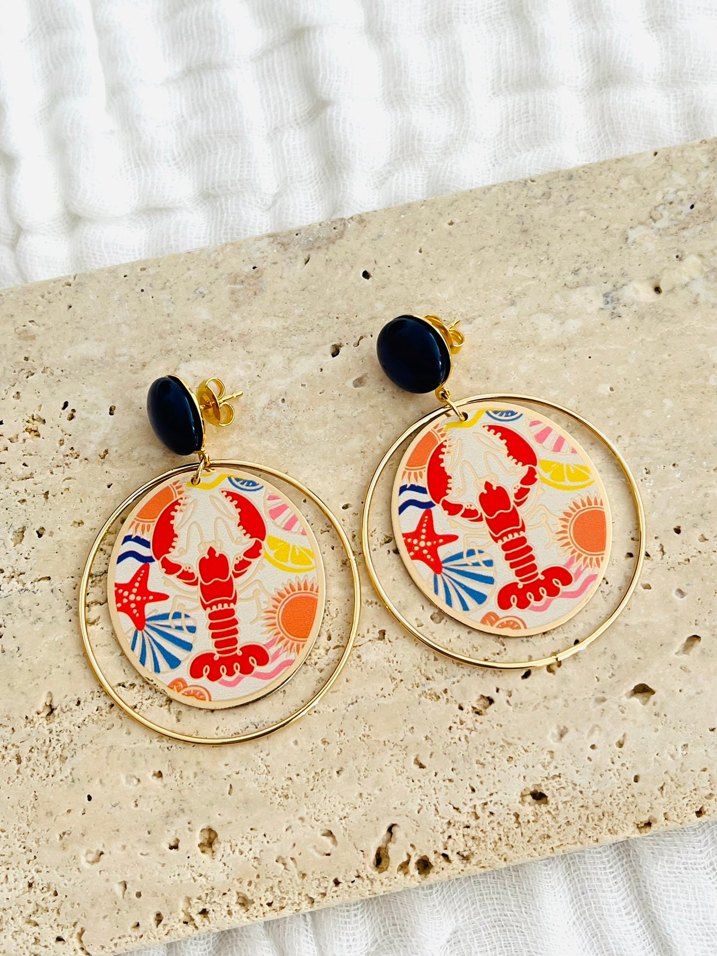 Boucles d'oreilles fantaisie fait main.
Clous d'oreilles en laiton doré à l'or fin rehaussé d'un cabochon bleu marine.
Anneaux fermés en laiton plaqué or 18k.
Pendentifs ronds imprimé homard, étoile de mer, coquillage, soleil.
Bijou fait main.