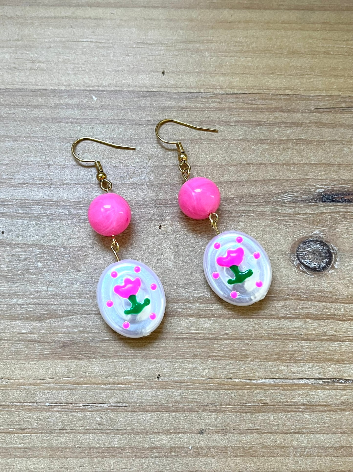 Boucles d'oreilles fantaisie fait main.
Crochets en acier inox doré.
Perles rondes en acrylique rose vif.
Perles ovale en acrylique blanc nacré avec motif tulipe.
Bijou fantaisie fait main.