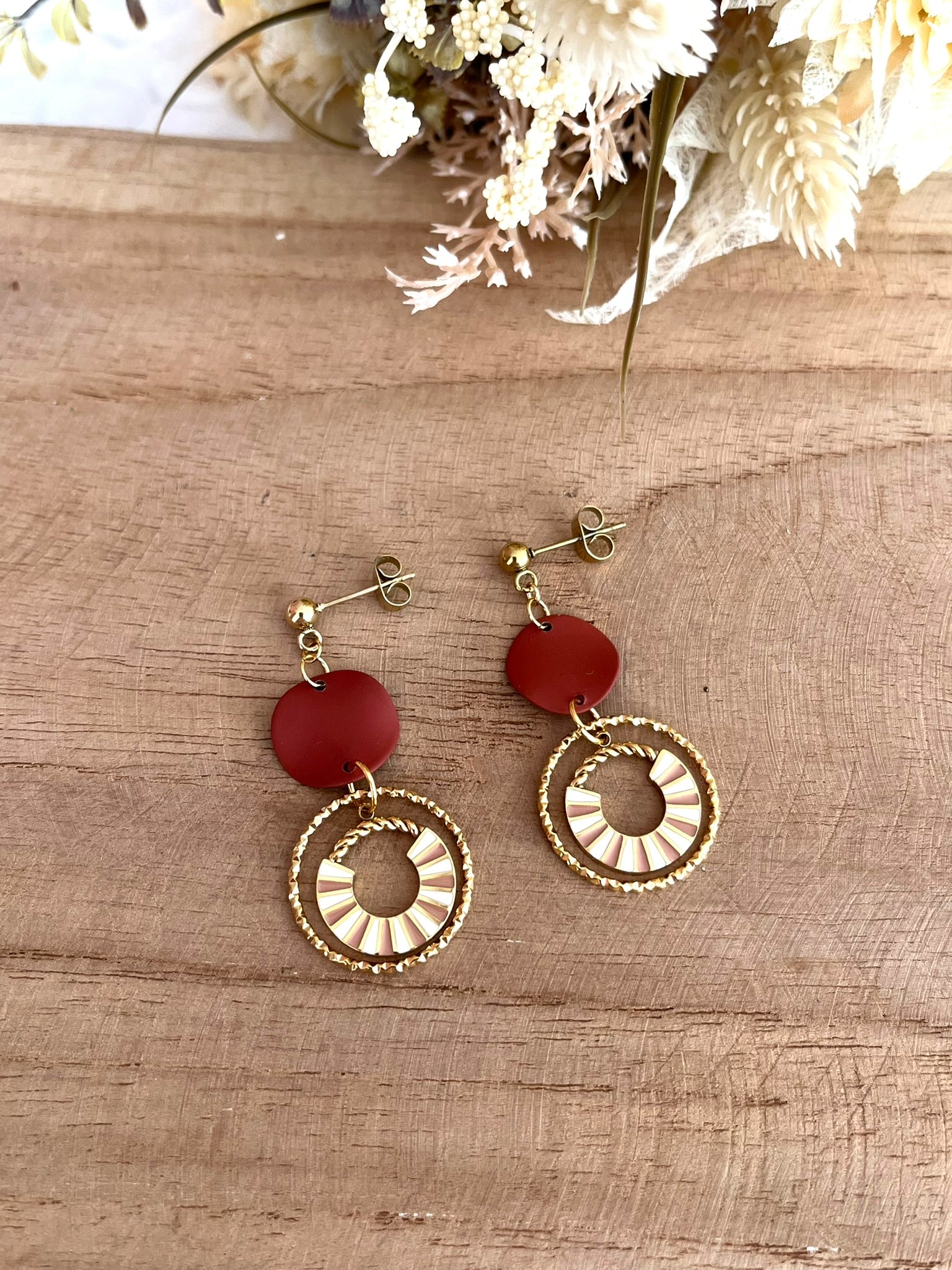 Boucles d'oreilles fantaisie fait main.
Clous d'oreilles en acier doré, sequin ondulé marron, pendentif design en acier doré et émail rose et blanc.
Bijou artisanal fait main.