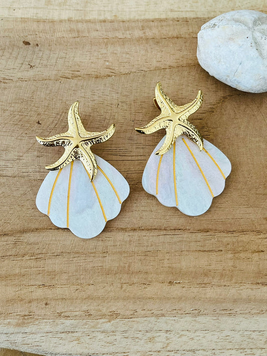 Boucles d'oreilles fantaisie fait main en acier inoxydable et acrylique.
Clous d'oreilles étoile de mer en acier inoxydable doré. Pendentifs coquillage éventail en acrylique blanc pailleté