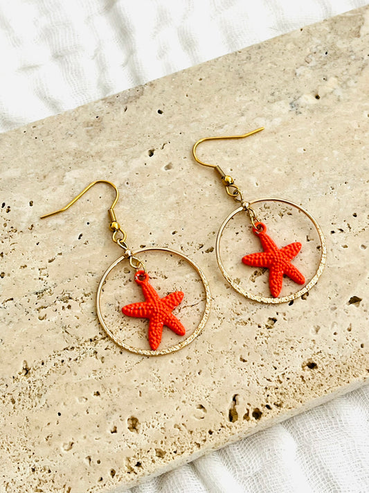 Boucles d'oreilles fantaisie fait main.
Crochets d'oreilles en acier inox doré, pendentifs ronds doré pailleté, breloque étoile de mer orange.
Bijou fait main.