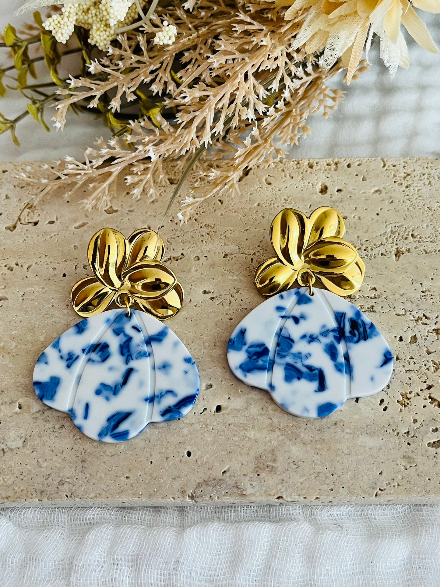 Boucles d'oreilles fantaisie fait main.
Clous d'oreilles fleur en acier inoxydable doré. Pendentifs pétale, éventail en acrylique bleu et blanc.
Bijou fait main.