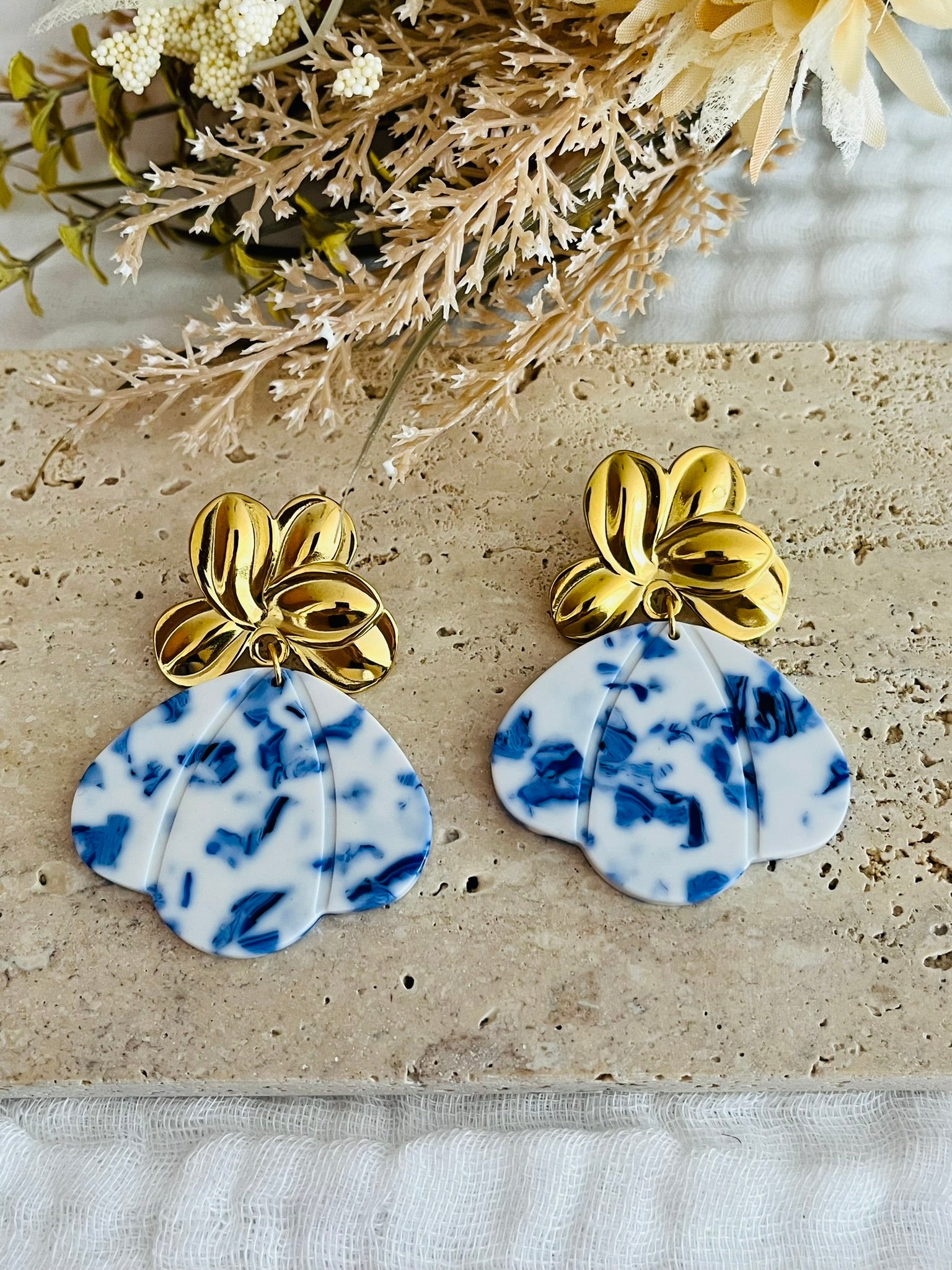 Boucles d'oreilles fantaisie fait main.
Clous d'oreilles fleur en acier inoxydable doré. Pendentifs pétale, éventail en acrylique bleu et blanc.
Bijou fait main.