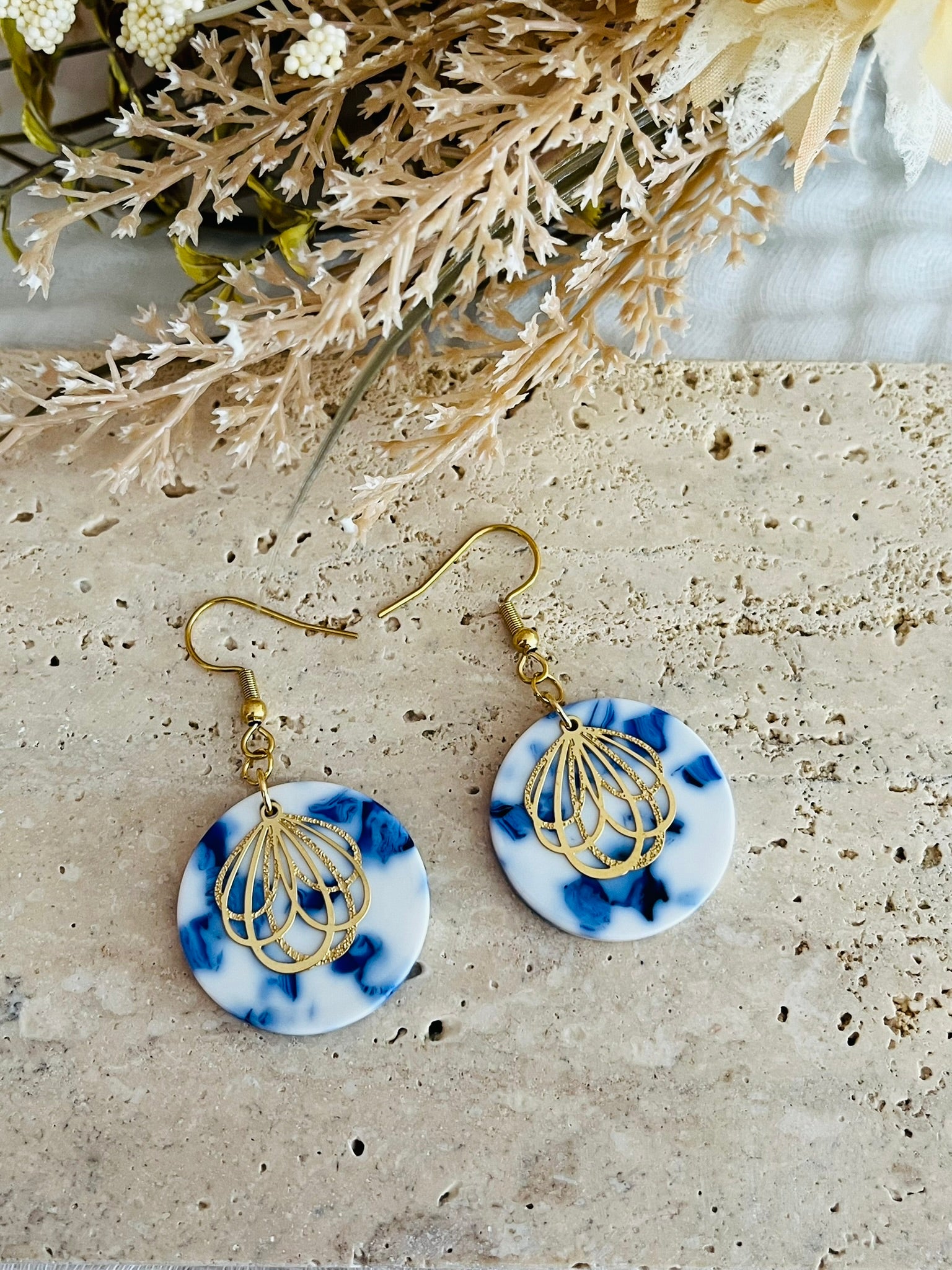 Boucles d'oreilles fantaisie fait main.
Crochets en acier inox doré. Pendentifs ronds en acrylique blanc marbré bleu. Estampe pétale de fleur en acier inox doré.
Bijou fantaisie fait main.
