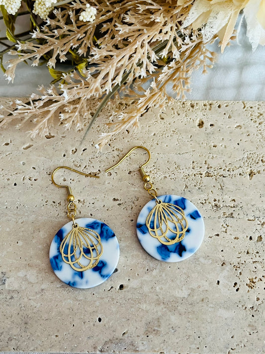 Boucles d'oreilles fantaisie fait main.
Crochets en acier inox doré. Pendentifs ronds en acrylique blanc marbré bleu. Estampe pétale de fleur en acier inox doré.
Bijou fantaisie fait main.