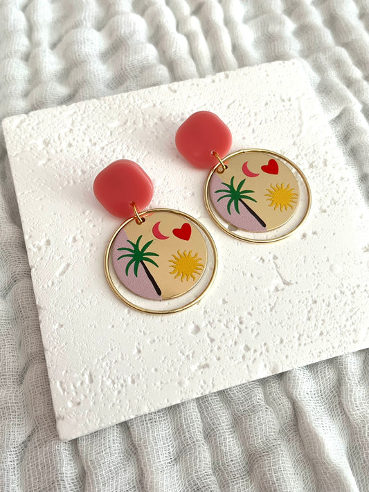 Boucles d'oreilles fantaisie fait main.
Clous d'oreilles en acrylique rose, anneaux fermés en laiton or 18k, pendentifs ronds bicolores doré et rose imprimé palmier, coeur, lune, soleil.
Bijou fantaisie fait main