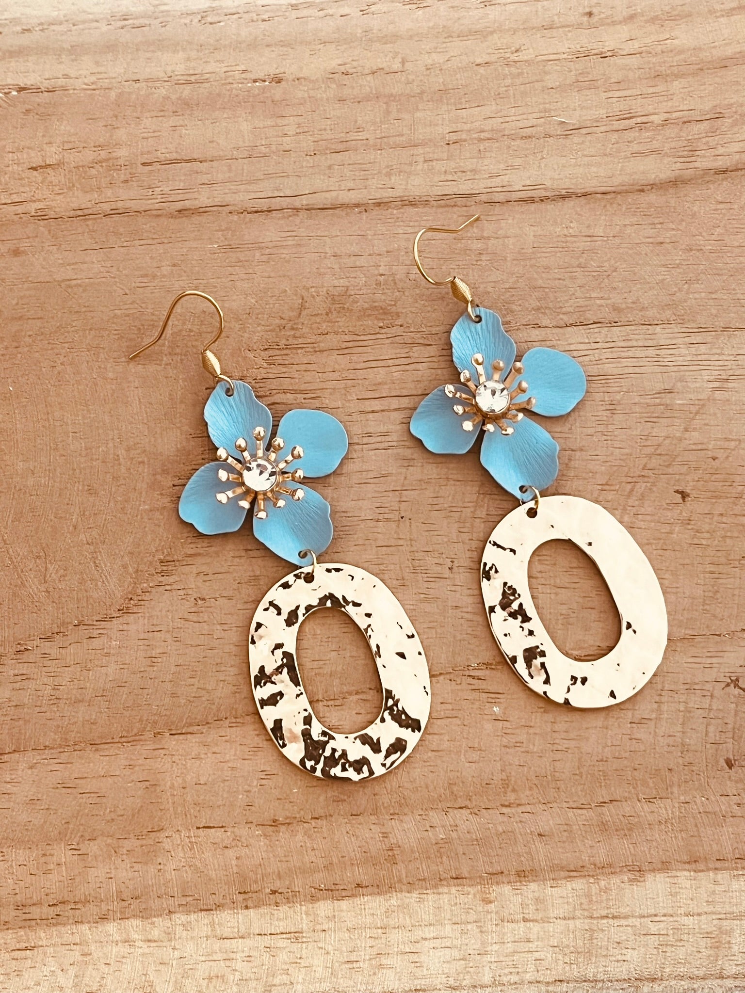 Boucles d'oreilles fantaisie pendantes  fleur bleu ciel avec un strass. Pendentifs ovales martelés doré.
Bijou fantaisie fait main