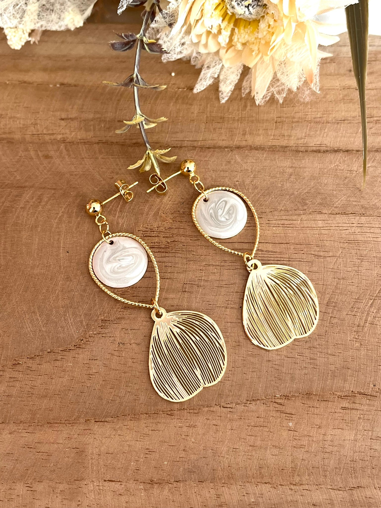 Boucles d'oreilles fantaisie fait main.
Clous d'oreilles doré, gouttes ciselées et estampes feuille en laiton doré à l'or fin 18k. Sequins ronds blanc nacré.
Bijou fantaisie fait main.