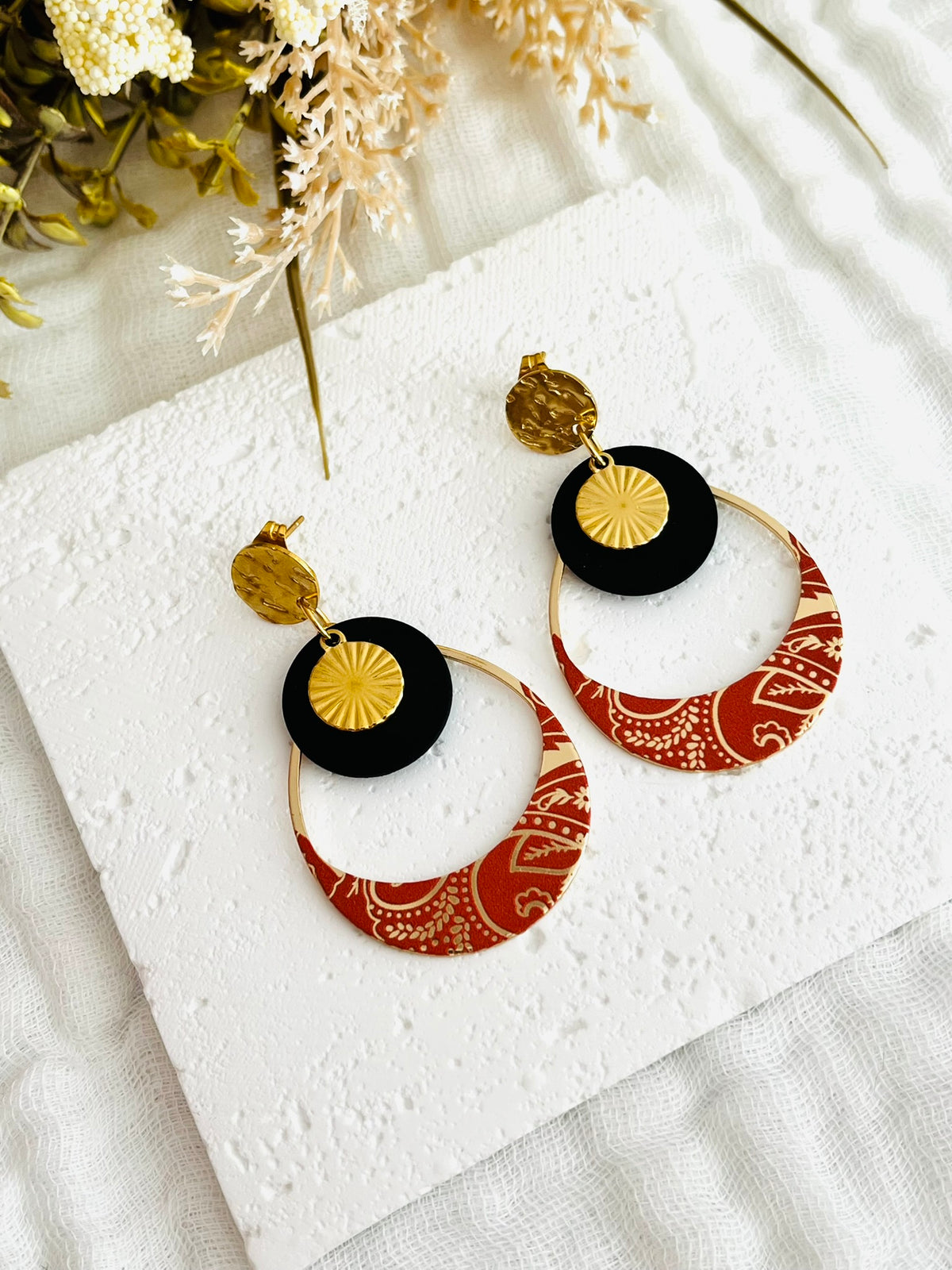 Boucles d'oreilles fantaisie fait main.
Clous d'oreilles ronds martelés en acier doré. Sequins ronds noir mat, pendentif goutte motif bandana terracotta et doré.
Bijou fantaisie fait main.