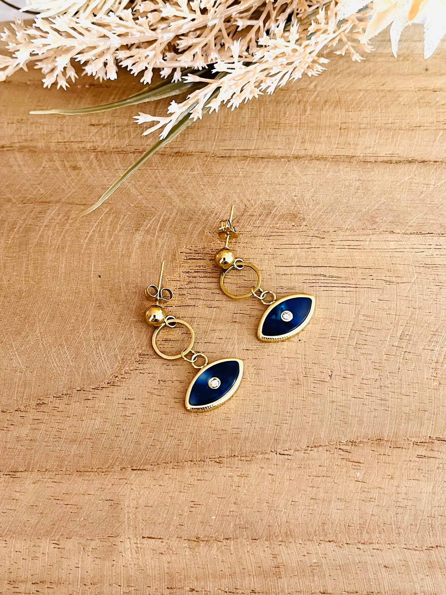 Boucles d'oreilles fantaisie fait main.
Clous d'oreilles en acier inoxydable doré, pendentif oeil bleu foncé.
Bijou fantaisie fait main.