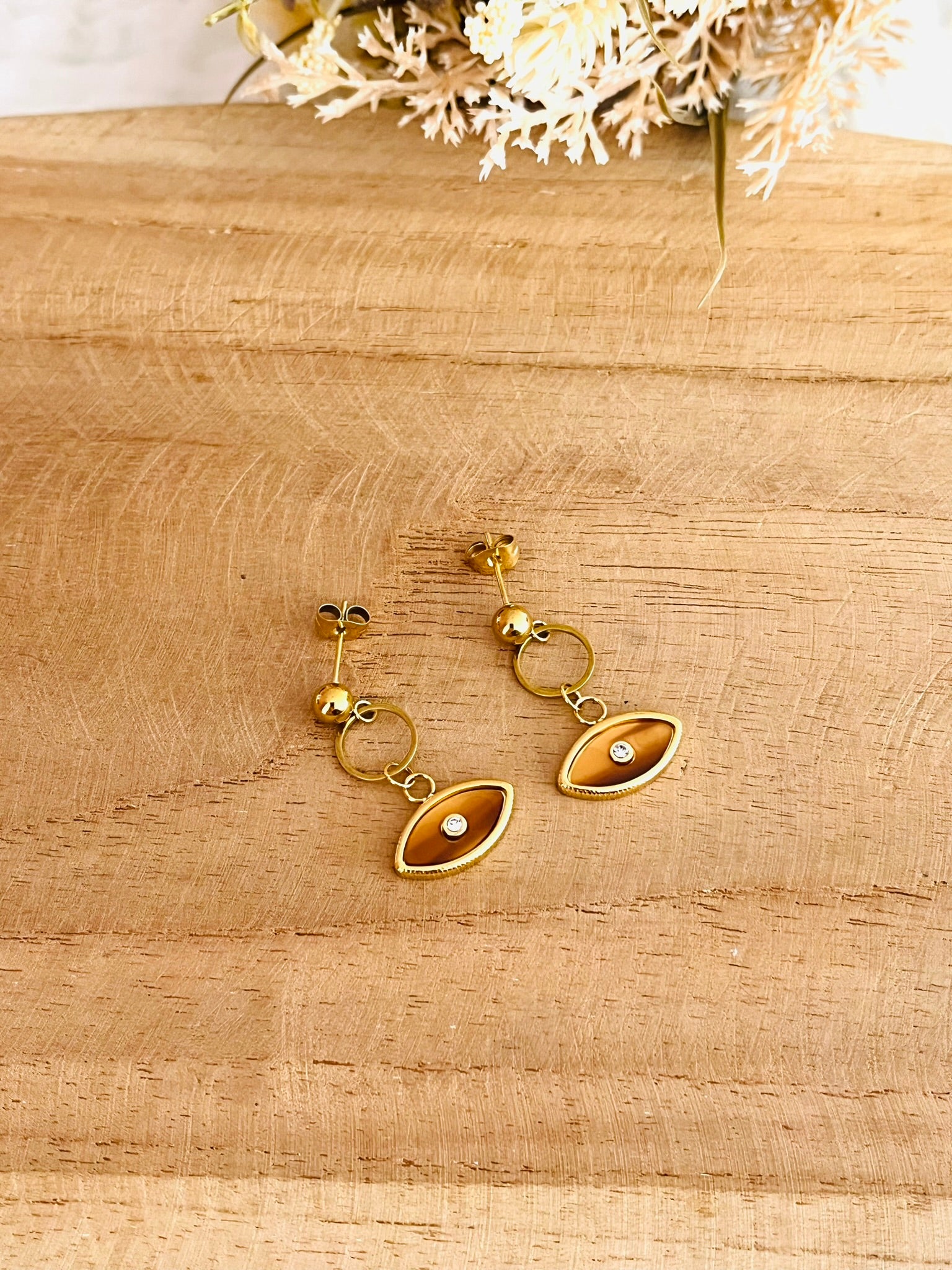 Boucles d'oreilles fantaisie fait main.
Clous d'oreilles en acier inoxydable doré, pendentif oeil marron ambre.
Bijou fantaisie fait main.
