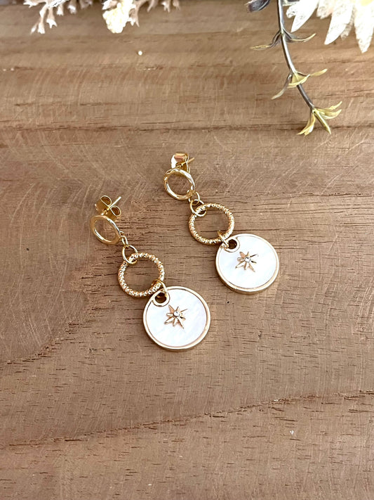 Boucles d'oreilles fantaisie fait main.
Clous d'oreilles cercle en laiton plaqué or 18k. Pendentif en nacre avec étoile polaire serti d'un strass.
Bijou fantaisie fait main.