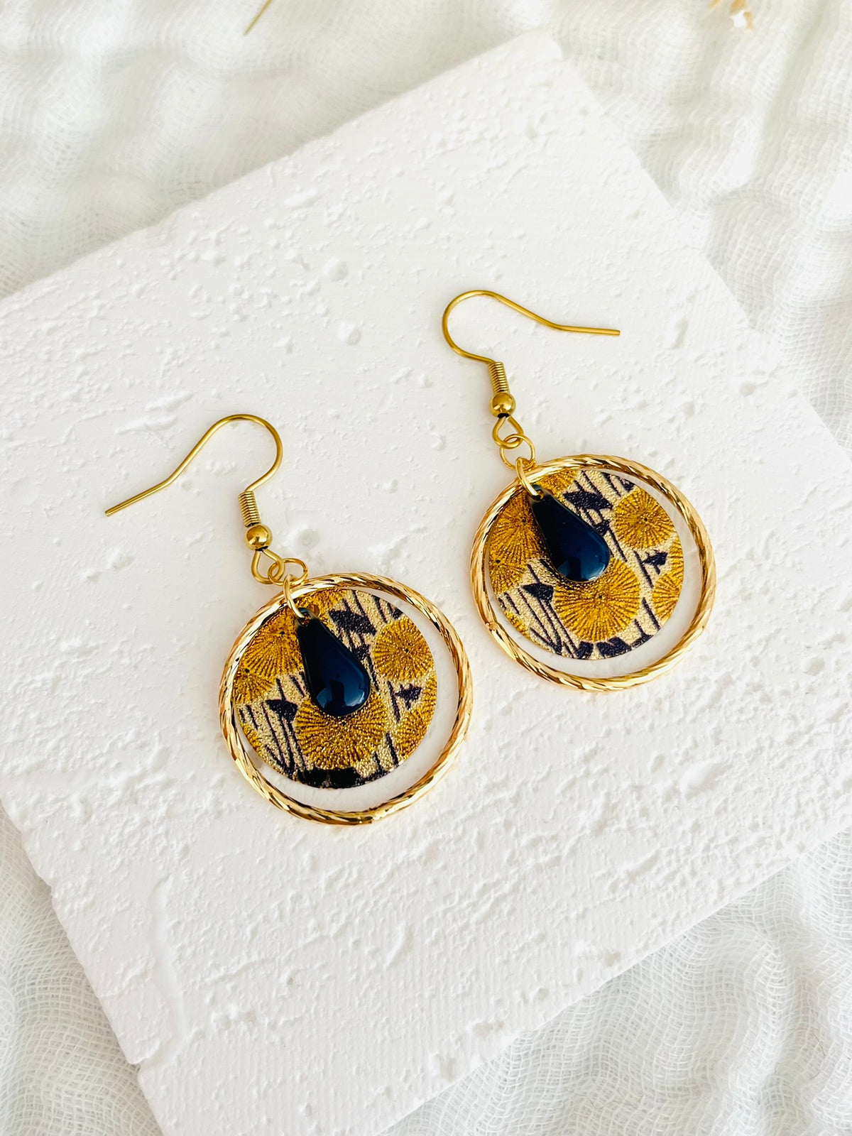 Boucles d'oreilles fantaisie fait main.
Crochets d'oreilles en acier inox doré; anneaux fermés torsadé en laiton plaqué or 18k; sequins ronds pailletés motif fleur jaune et bleu marine; sequin goutte émaillé bleu marine
Bijou fait main