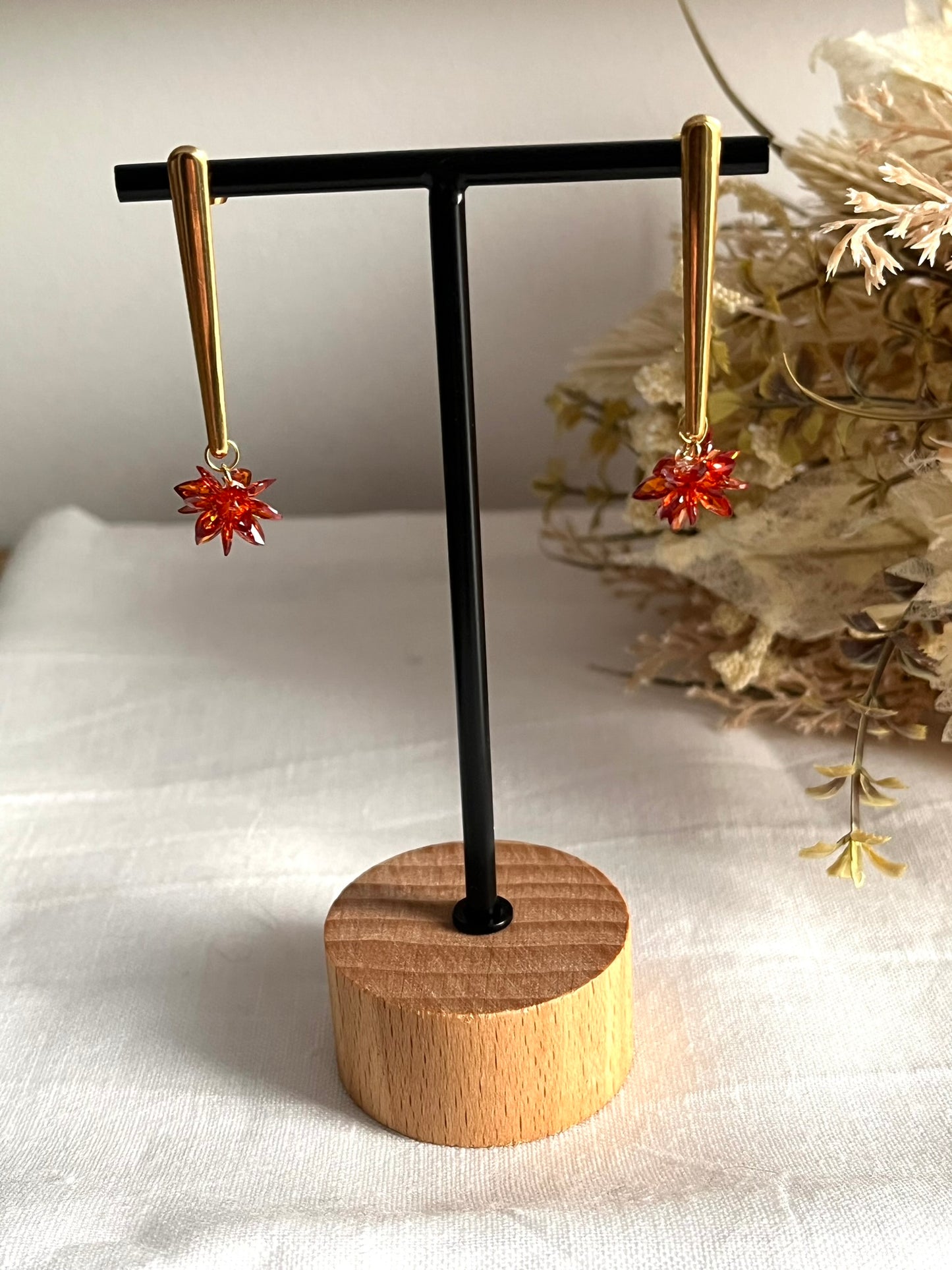 Boucles d'oreilles fantaisie fait main.
Clous d'oreilles longue barre en acier inoxydable doré. Pendentif fleur étoilée en verre cristal de couleur rouille.
Bijou fantaisie fait main.