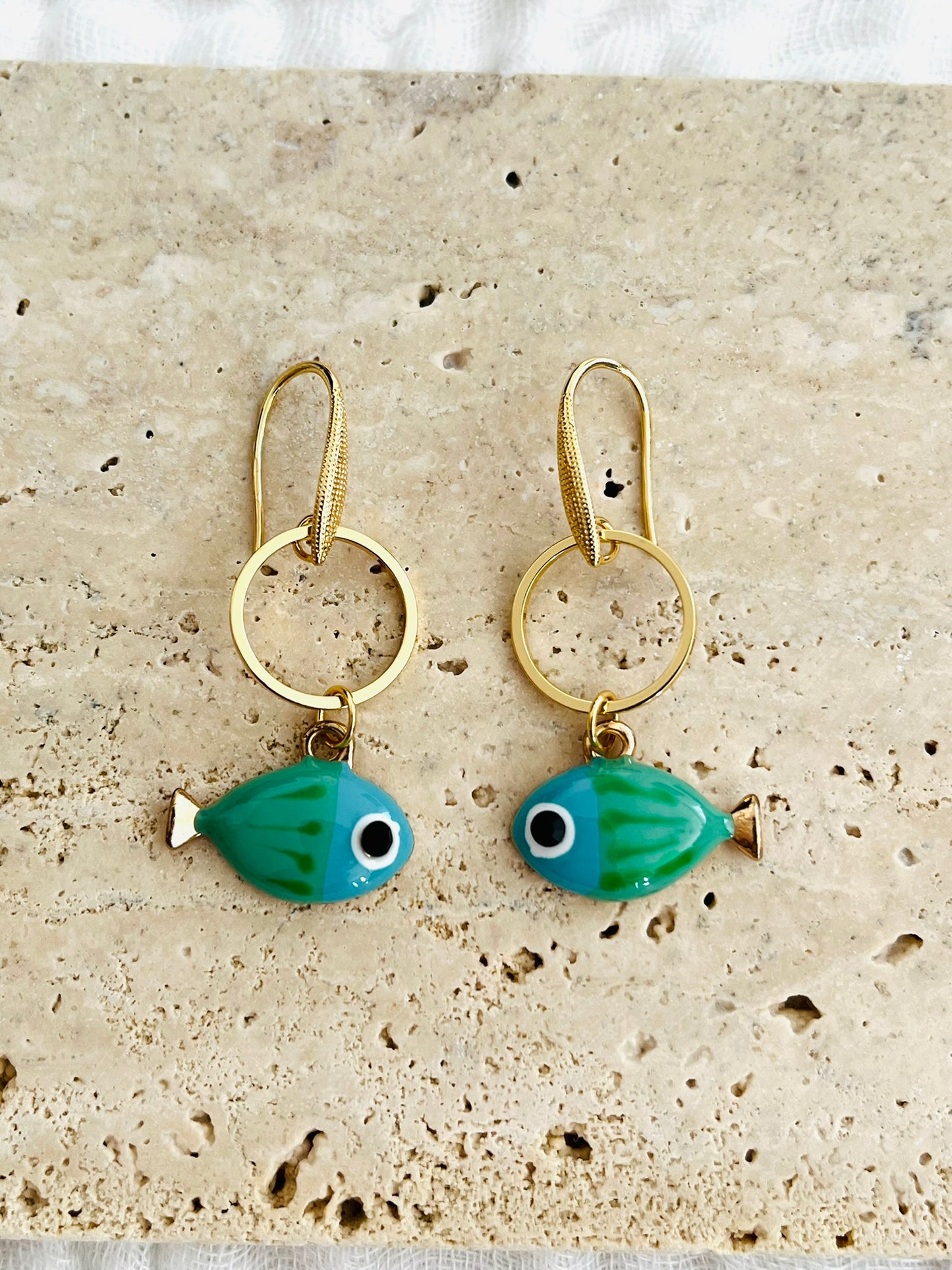Bijou fantaisie fait main.
Crochets de boucles d'oreilles en laiton plaqué or 18k.
Anneaux fermes de 15mm en laiton plaqué or 18k.
Breloques poisson émaillé vert et bleu.
Bijou fait main.