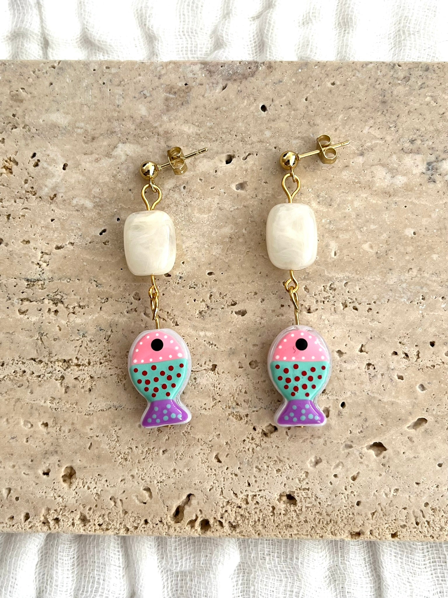 Boucles d'oreilles fantaisie fait main.
Clous d'oreilles boule en acier inox doré;
Perle rectangle en acrylique écru;
Perle poisson en verre rose, turquoise, violet.
Bijou fait main.