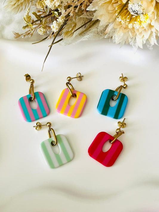 Boucles d'oreilles fantaisie fait main.
Clous d'oreilles en acier inoxydable doré. Pendentif carré en acrylique rayés.
Bijou fait main