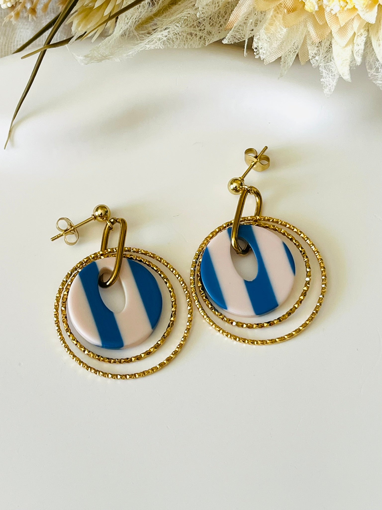 Boucles d'oreilles fantaisie fait main.
Clous d'oreilles en acier doré.
Jeu d'anneaux ciselés de 25 et 30mm en acier doré.
Pendentifs ronds en acrylique rayés bleu et blanc.
Bijou fantaisie fait main.