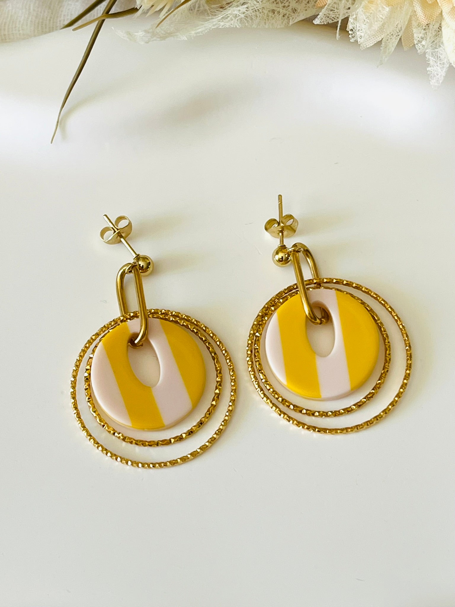 Boucles d'oreilles fantaisie fait main.
Clous d'oreilles en acier doré.
Jeu d'anneaux ciselés de 25 et 30mm en acier doré.
Pendentifs ronds en acrylique rayés jaune et blanc.
Bijou fantaisie fait main.