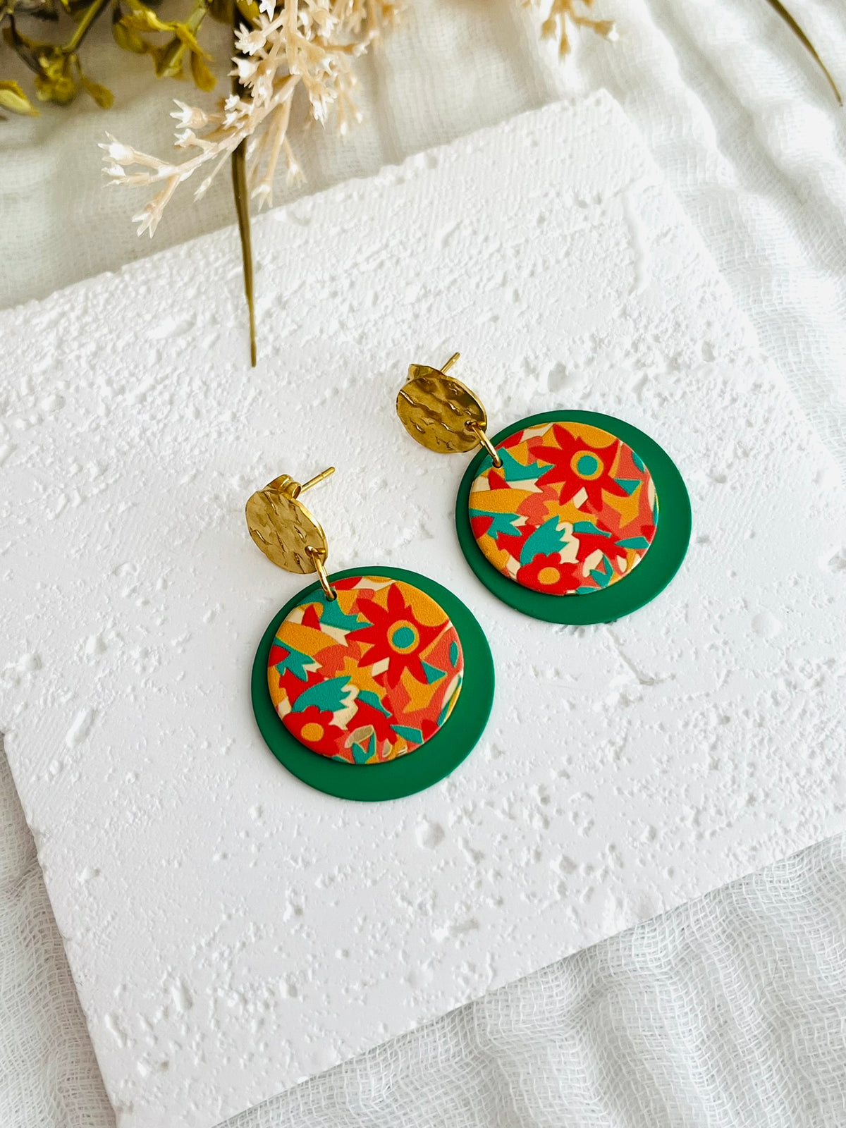 Boucles d'oreilles fantaisie fait main.
Clous d'oreilles ronds martelés en acier inox doré.
Sequins ronds vert, pendentifs imprimés fleurs orange, vert, jaune.
Bijou fantaisie fait main.