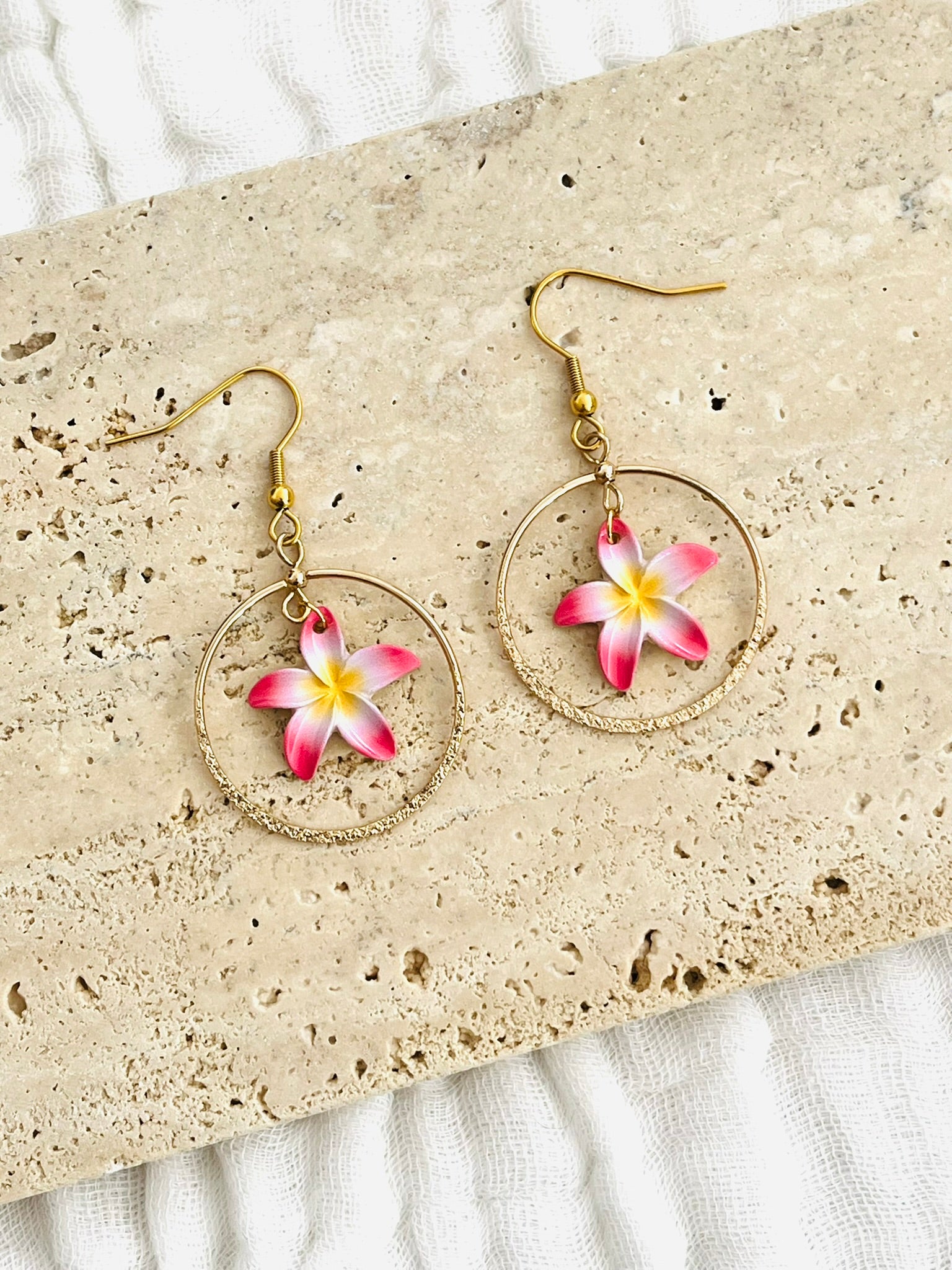 Boucles d'oreilles fantaisie fait main.
Crochets en acier doré, pendentif rond doré pailleté, breloque fleur de tiaré rose, blanc et jaune.
Bijou fait main