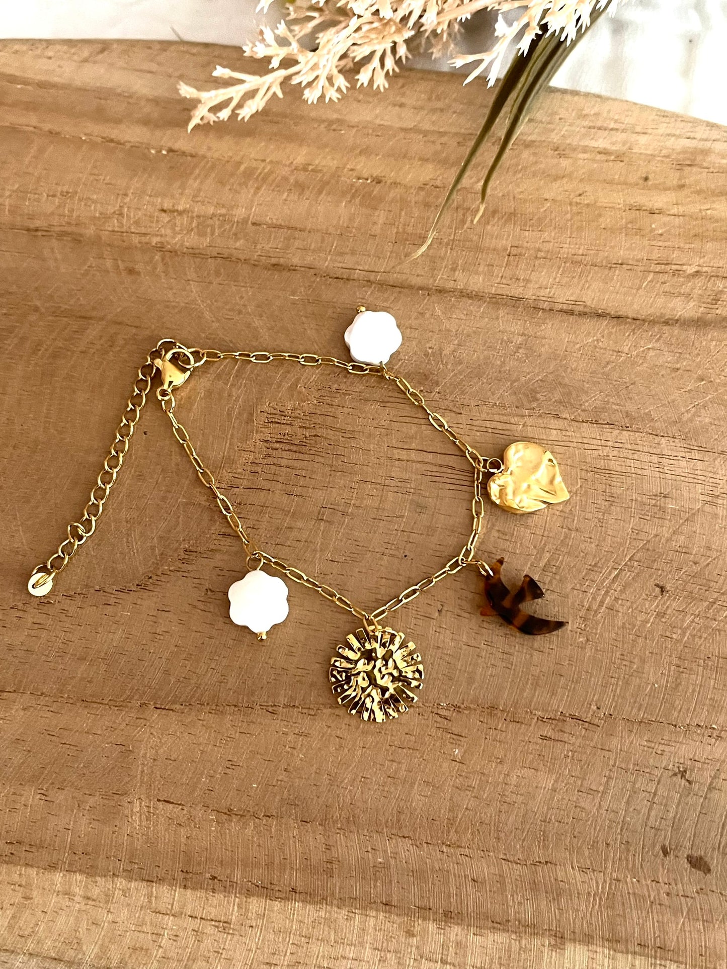 Bracelet fantaisie fait main.
Bracelet à charms en acier inoxydable doré orné de fleurs en nacre, une hirondelle en acrylique marron et noir, un soleil et un coeur martelé en acier doré.
Bijou fantaisie fait main.