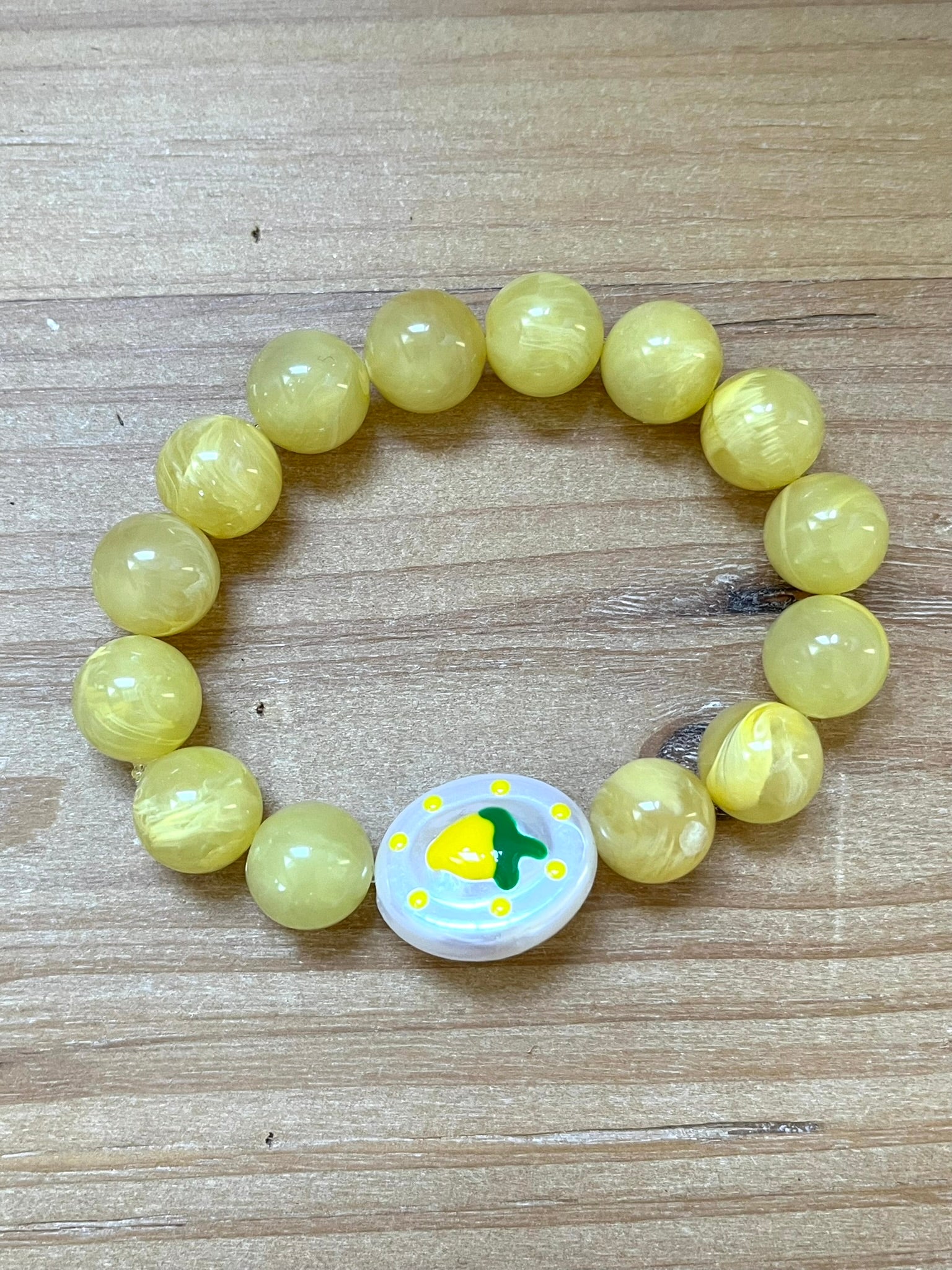 Bracelet fantaisie fait main monté sur élastique.
Perles rondes en acrylique jaune de 12mm.
Perle ovale en acrylique blanc nacré avec motif citron.
Bijou fantaisie fait main.