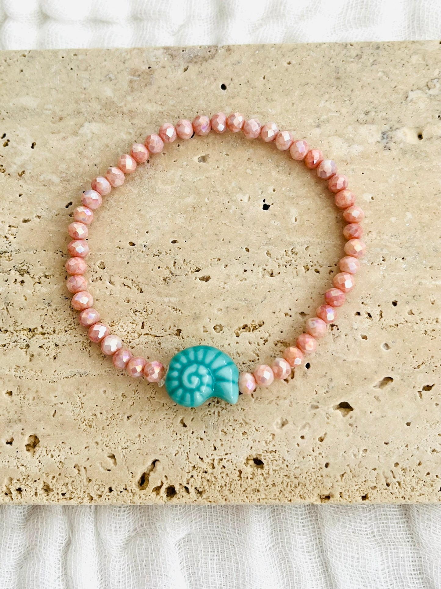 Bracelet élastique fait main.
Perles en verre facettées rose et perle coquillage en céramique turquoise.
Bijou fait main.