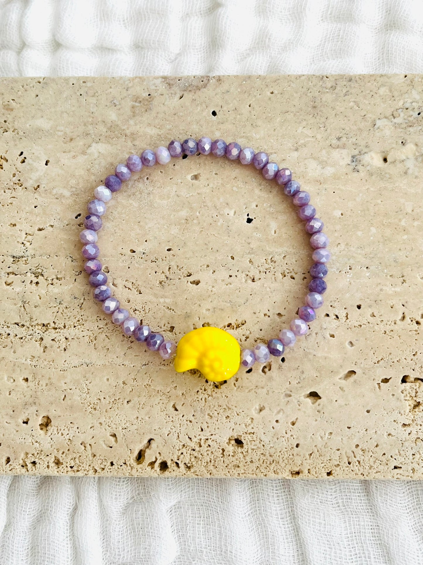 Bracelet élastique fait main.
Perles en verre facettées violet et perle coquillage en céramique jaune.
Bijou fait main.