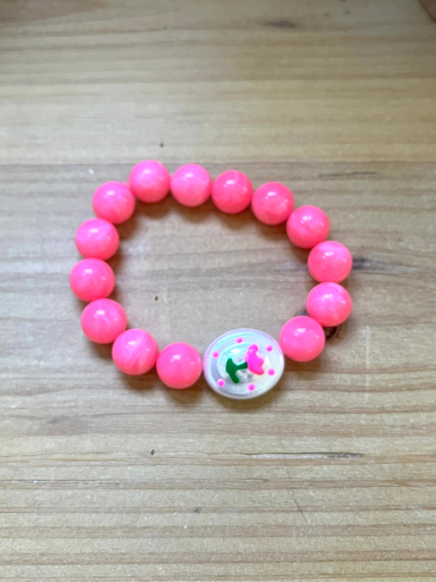 Bracelet fantaisie fait main monté sur élastique.
Perles rondes en acrylique rose vif de 12mm.
Perle ovale en acrylique blanc nacré avec motif tulipe rose.
Bijou fantaisie fait main.