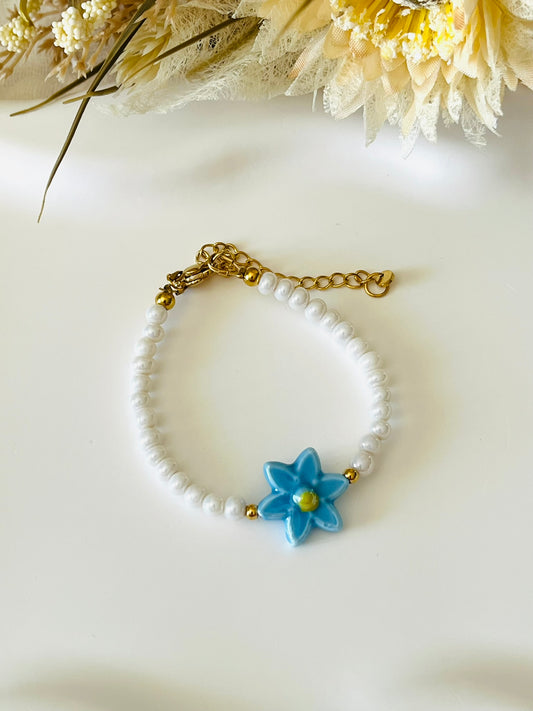 Bracelet fantaisie fait main.
Perles en verre blanc nacré, perle fleur en céramique bleu.
Fermoir en acier inox doré.
Bijou fait main.