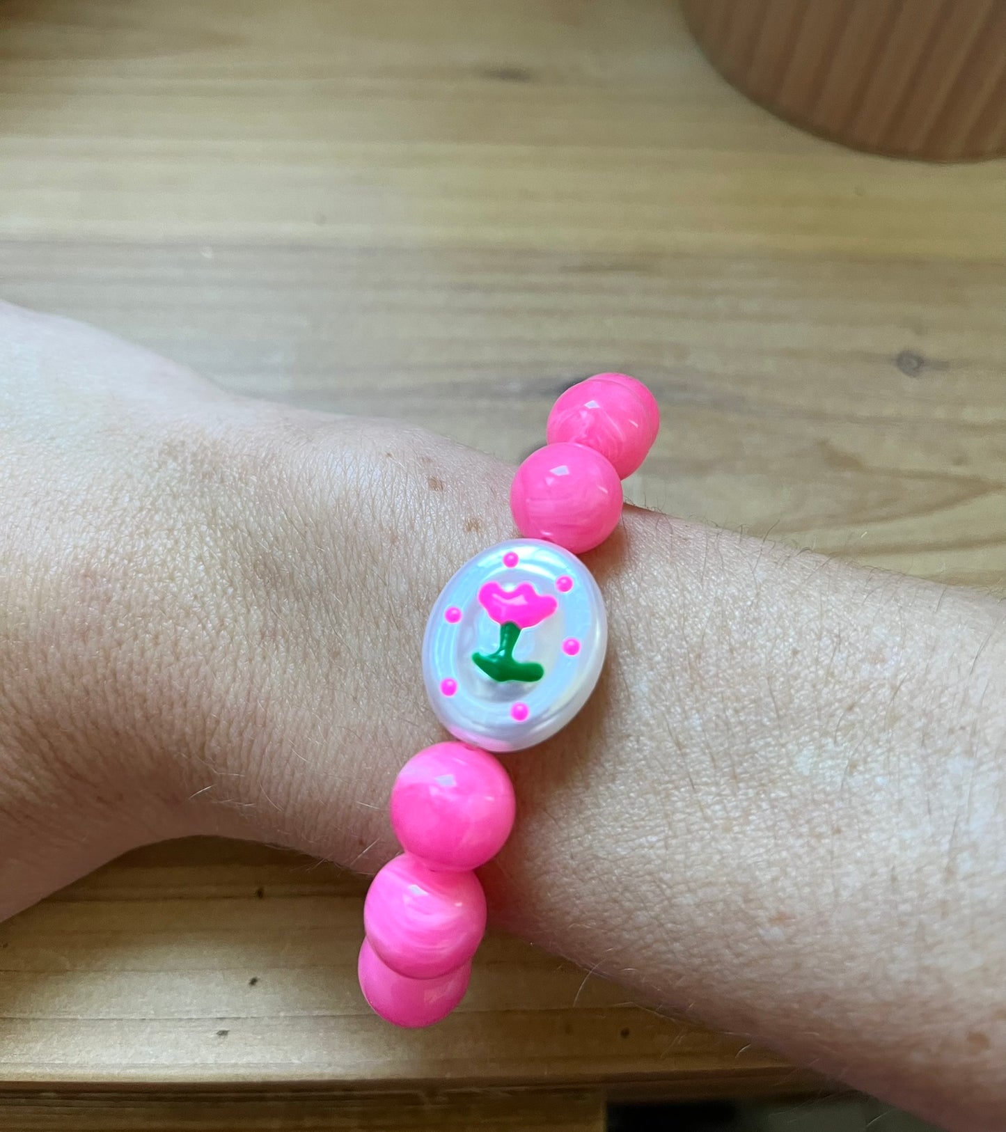 Bracelet fantaisie fait main monté sur élastique.
Perles rondes en acrylique rose vif de 12mm.
Perle ovale en acrylique blanc nacré avec motif tulipe rose.
Bijou fantaisie fait main.