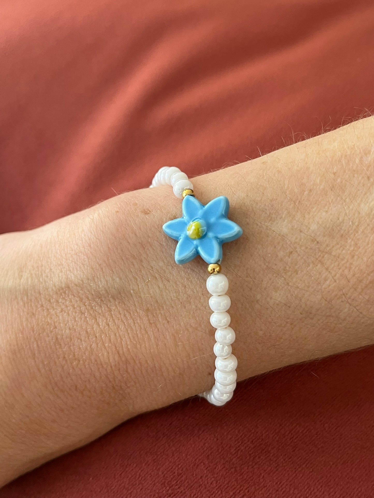 Bracelet fantaisie fait main.
Perles en verre blanc nacré, perle fleur en céramique bleu.
Fermoir en acier inox doré.
Bijou fait main.