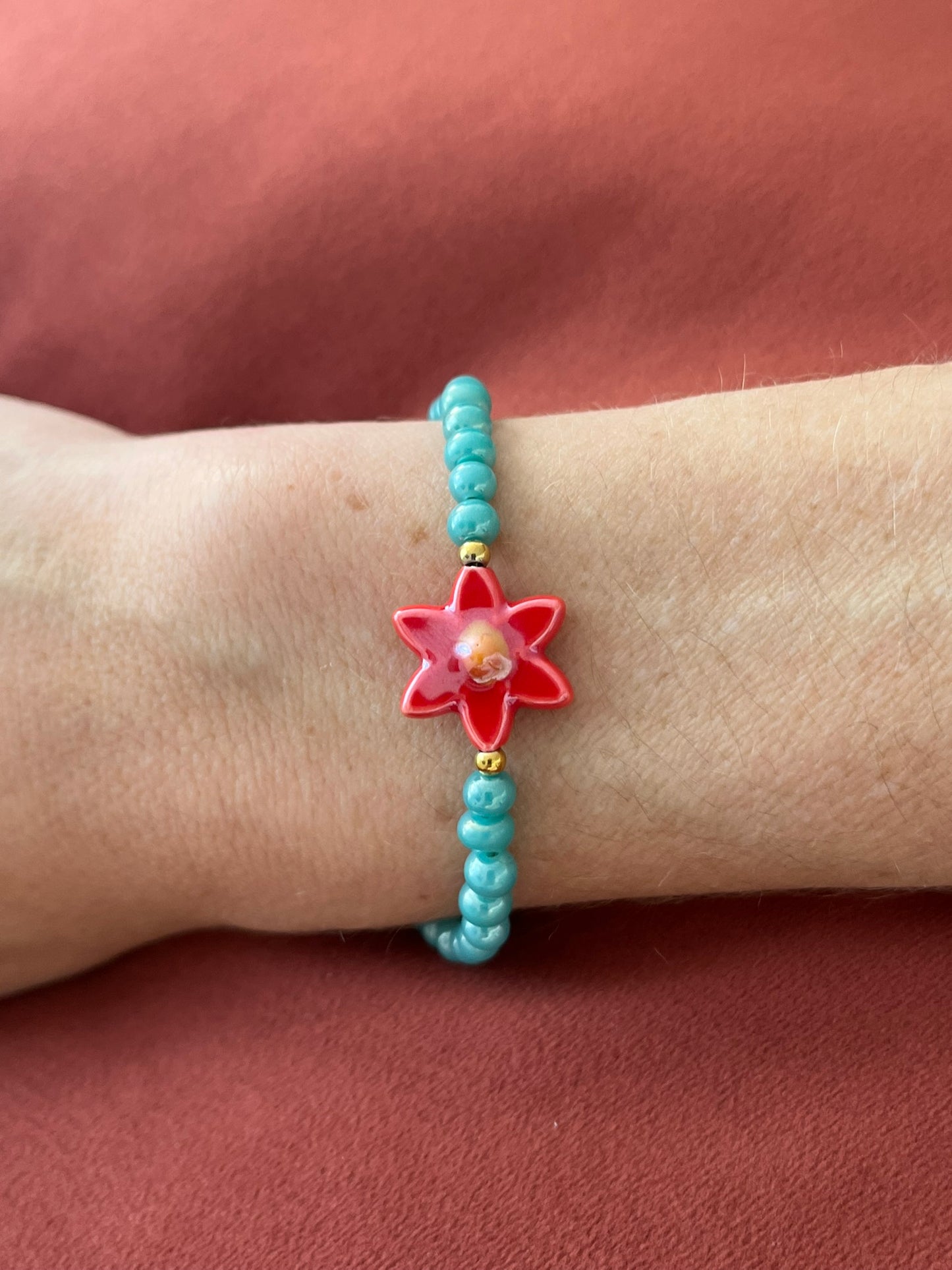Bracelet fantaisie fait main.
Perles en verre turquoise nacré, perle fleur en céramique rouge.
Fermoir en acier inox doré.
Bijou fait main.