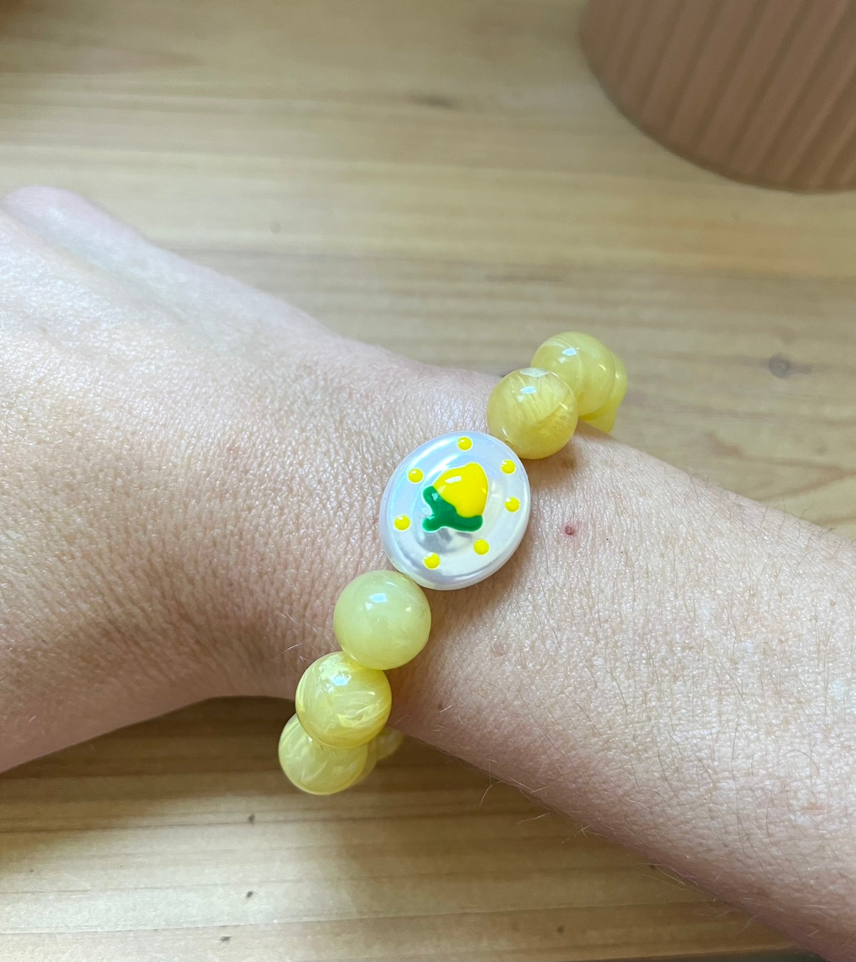 Bracelet fantaisie fait main monté sur élastique.
Perles rondes en acrylique jaune de 12mm.
Perle ovale en acrylique blanc nacré avec motif citron.
Bijou fantaisie fait main.