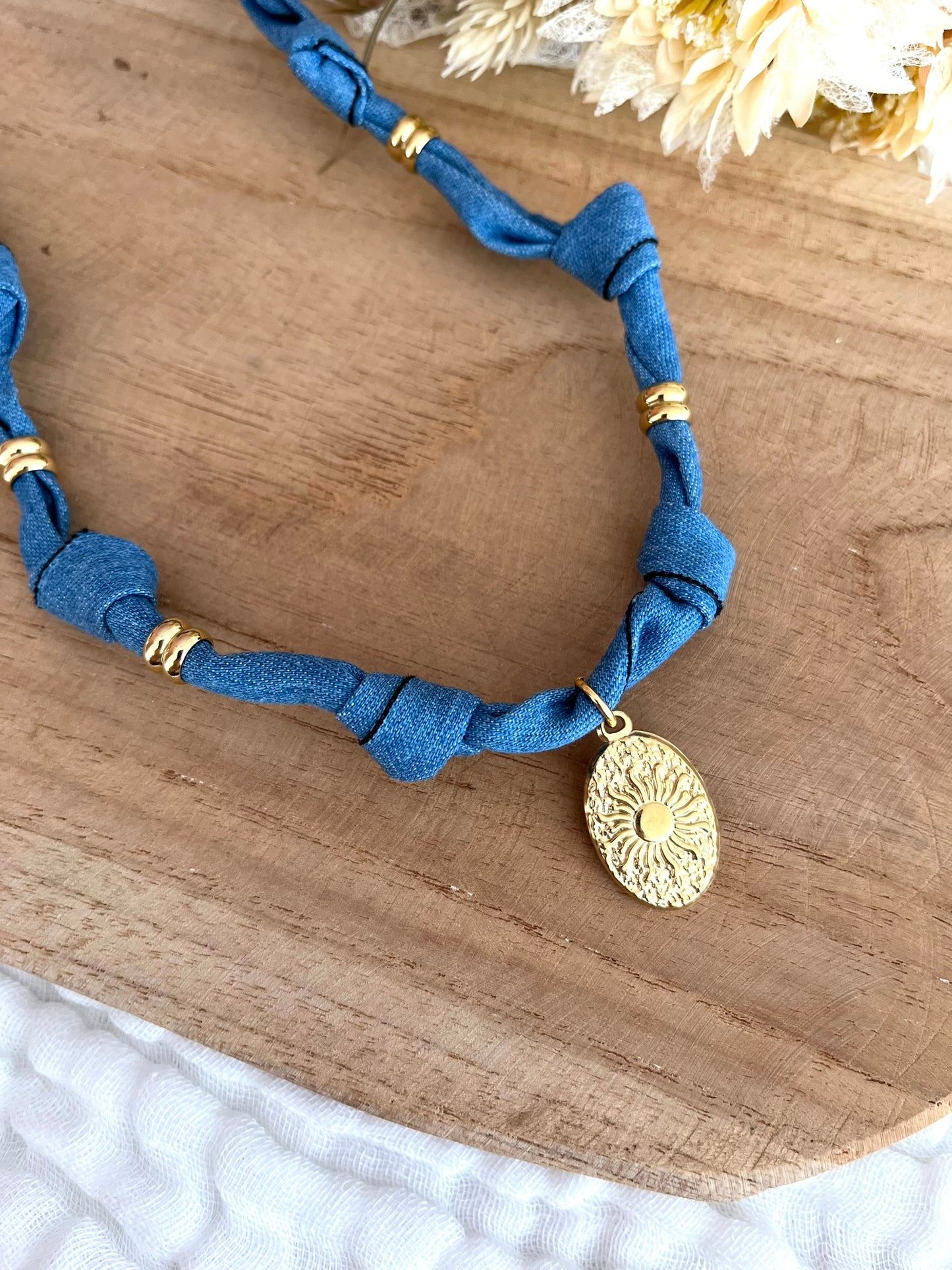 Collier en tissu bleu denim et pendentif ovale motif soleil.
Tissu en coton denim et pendentif en acier inoxydable doré.
Longueur: 44cm + 5cm
Bijou fantaisie fait main.