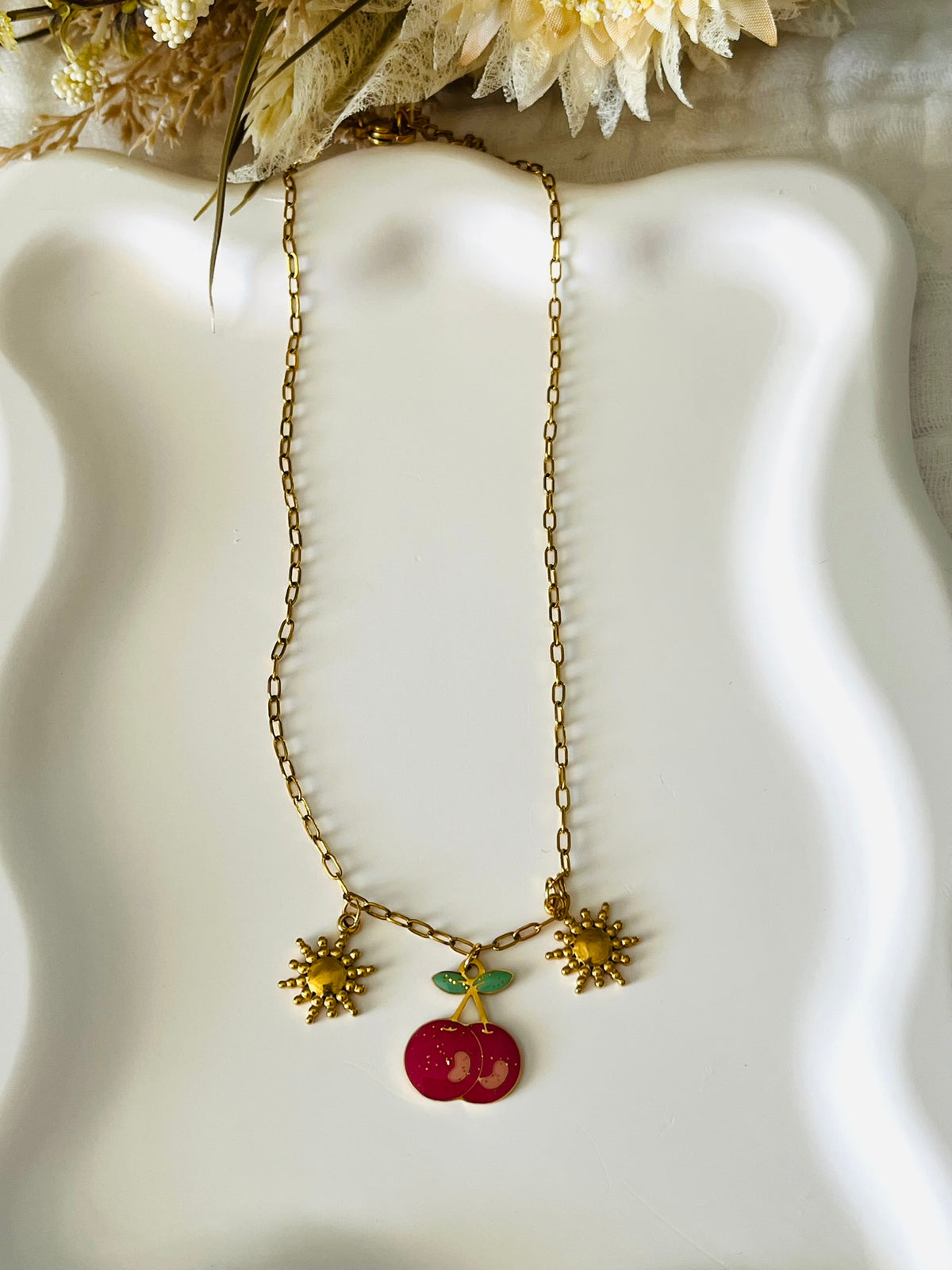 Collier adapté pour les enfants à partir de 6 ans.
Collier en acier inoxydable doré, hypoallergénique.
Breloque cerise rose pailleté et soleils dorés