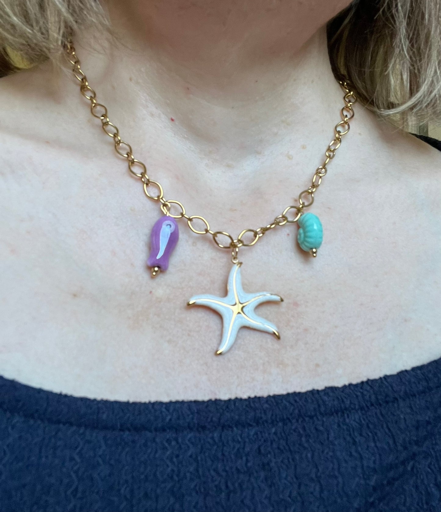 Bijou fantaisie en acier inoxydable doré fait main.
Collier gros maillons en acier inox ajustable de 42 à 47 cm.
Pendentif étoile de mer blanc nacré en acier inox.
Perle poisson violet en céramique, perle coquillage turquoise en céramique.