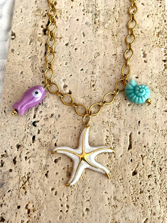 Bijou fantaisie en acier inoxydable doré fait main.
Collier gros maillons en acier inox ajustable de 42 à 47 cm.
Pendentif étoile de mer blanc nacré en acier inox.
Perle poisson violet en céramique, perle coquillage turquoise en céramique.