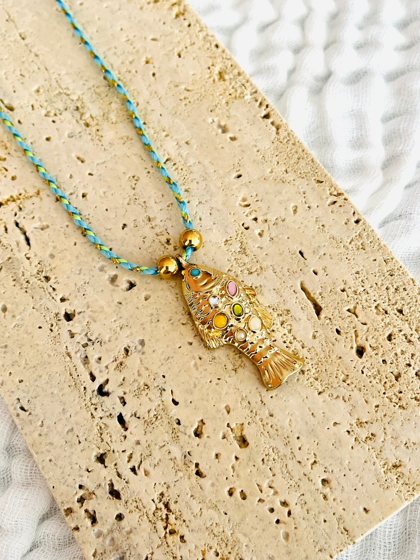 Collier fantaisie fait main.
Collier en cordon tresse en coton vert, turquoise, doré.
Pendentif poisson doré orné de pierres rose, jaune, vert.
Longueur de 41 à 46 cm.
Bijou fantaisie fait main.