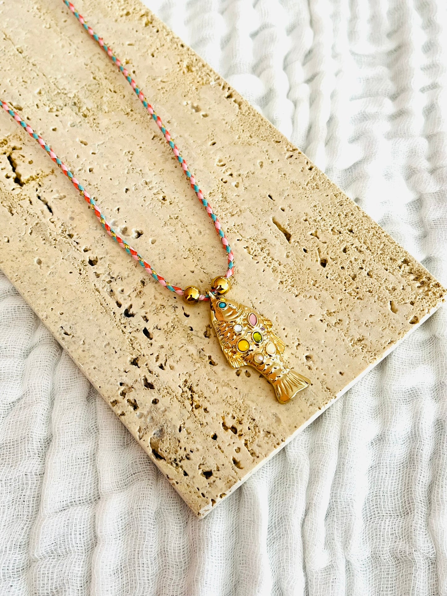 Collier fantaisie fait main.
Collier en cordon tresse en coton rose, turquoise, doré.
Pendentif poisson doré orné de pierres rose, jaune, vert.
Longueur de 41 à 46 cm.
Bijou fantaisie fait main.