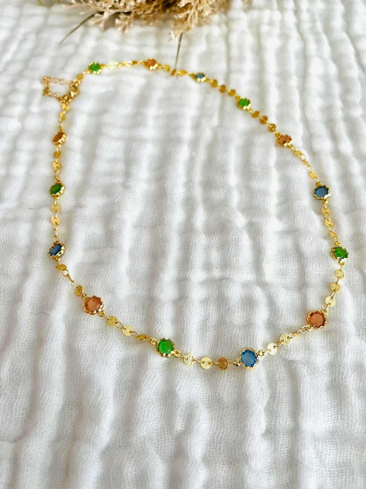 Collier fantaisie fait main.
Chaîne en laiton doré sertie de cristaux en verre rose, bleu, vert.