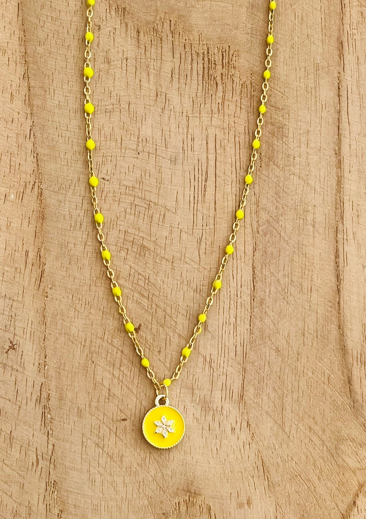 Collier fantaisie en acier inoxydable doré et résine époxy jaune.
Pendentif rond avec une fleur.
Bijou fantaisie fait main.