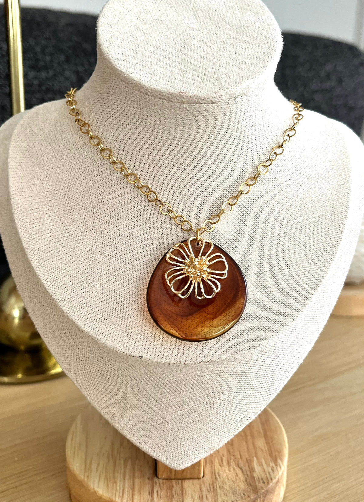 Collier fantaisie fait main.
Chaine à maillons ronds en acier doré; pendentif pétale en acrylique marron ambré, pendentif fleur en laiton or 18k.
Bijou fait main.