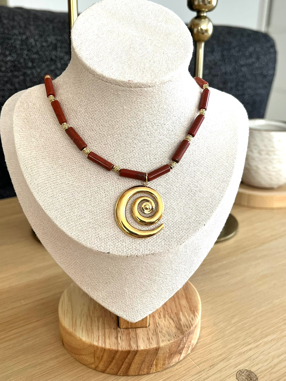 Collier fantaisie fait main.
Chaîne en acier doré et perles tubes en pierre naturelle jaspe rouge rouille.
Pendentif spirale en acier inox doré.
Bijou fait main.