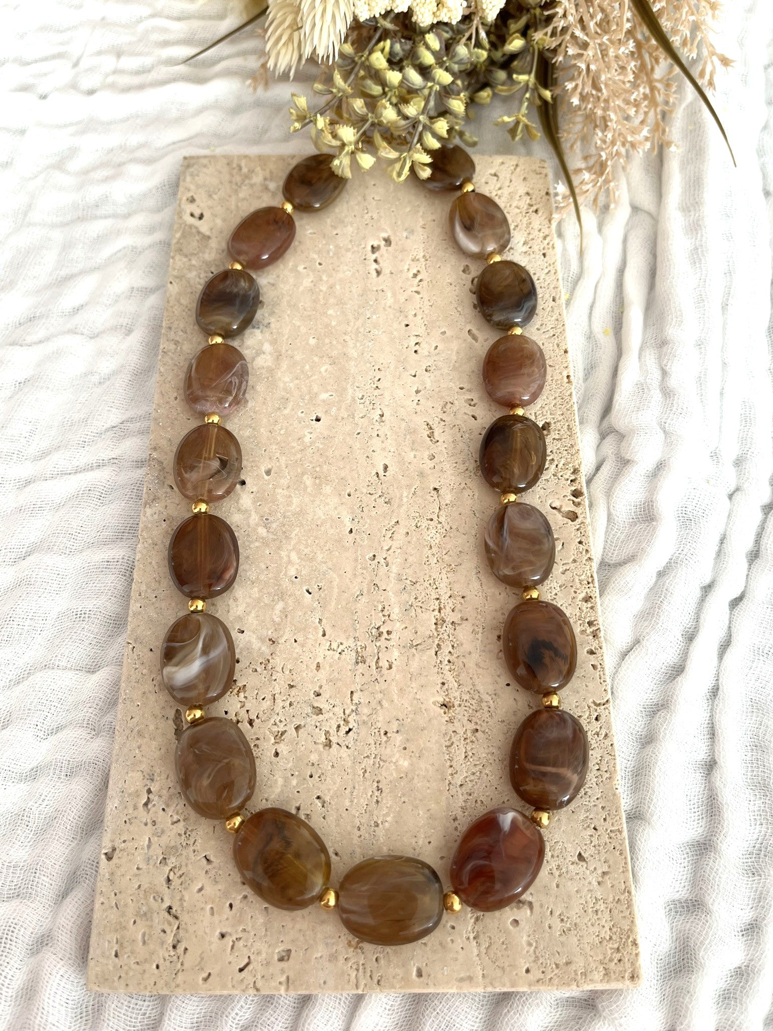 Collier fantaisie fait main.
Perles ovales en résine marron marbré.
Petites perles intercalaires ronde en acier doré.
Bijou fantaisie fait main.