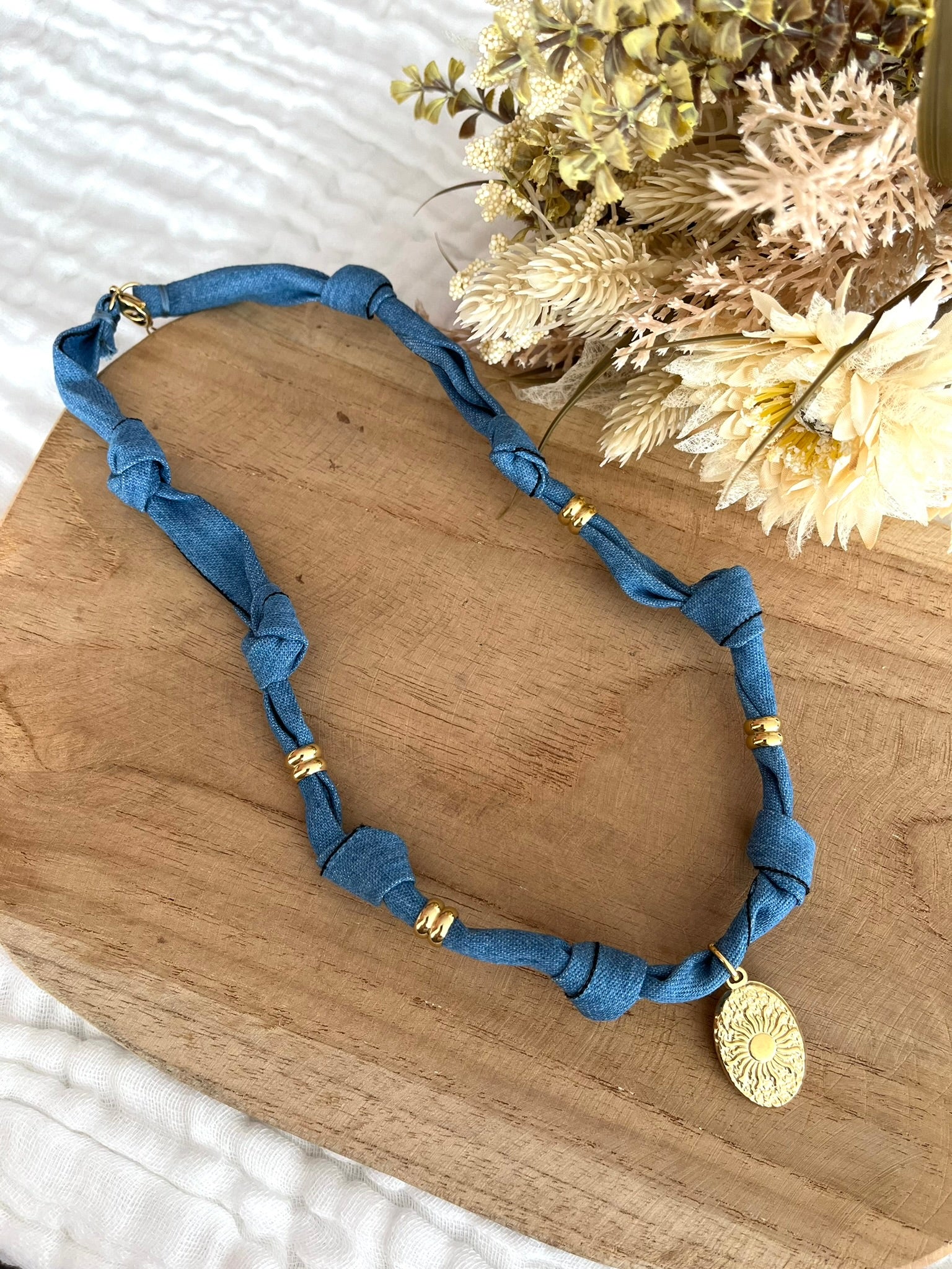 Collier en tissu bleu denim et pendentif ovale motif soleil.
Tissu en coton denim et pendentif en acier inoxydable doré.
Longueur: 44cm + 5cm
Bijou fantaisie fait main.